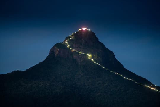  Night pilgrims climbing with lamps under a starry sky.