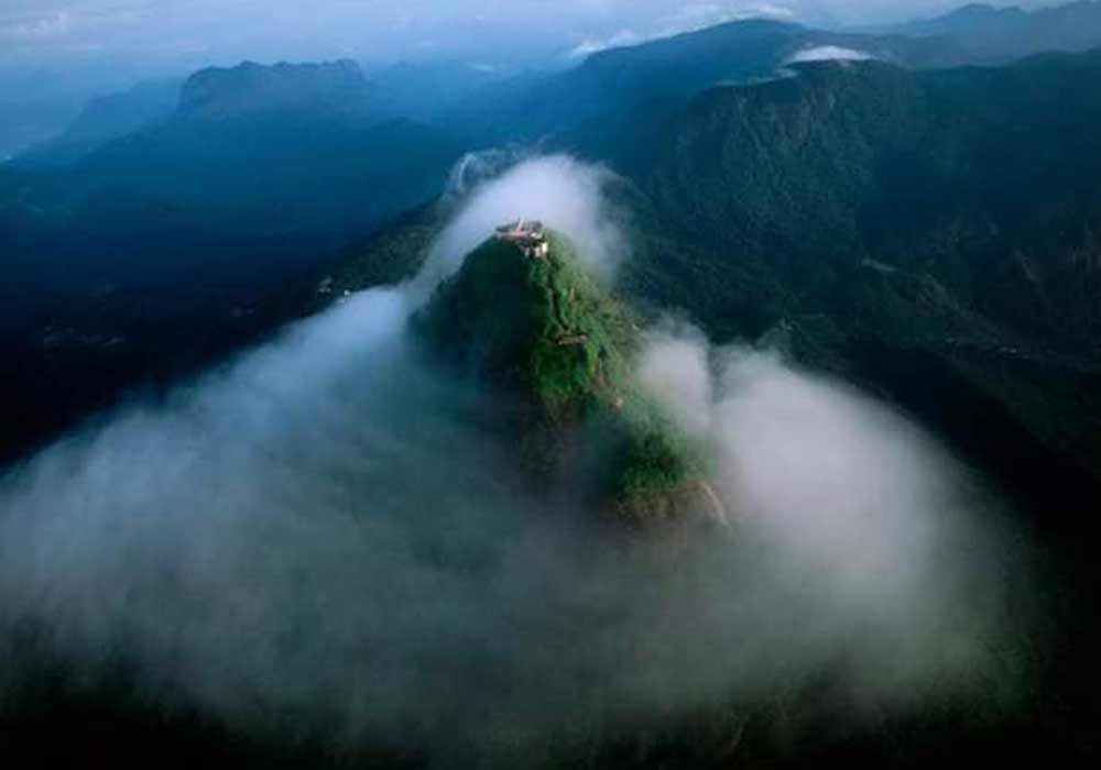 Pilgrims gathered at the summit as the sun rises beyond the clouds