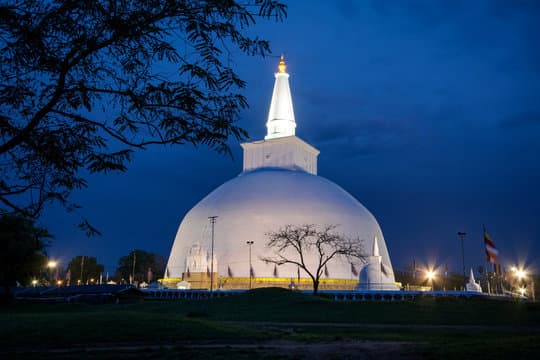 The grand white stupa of Ruwanwelisaya illuminated at dusk, a revered symbol of Sri Lankan Buddhism.
